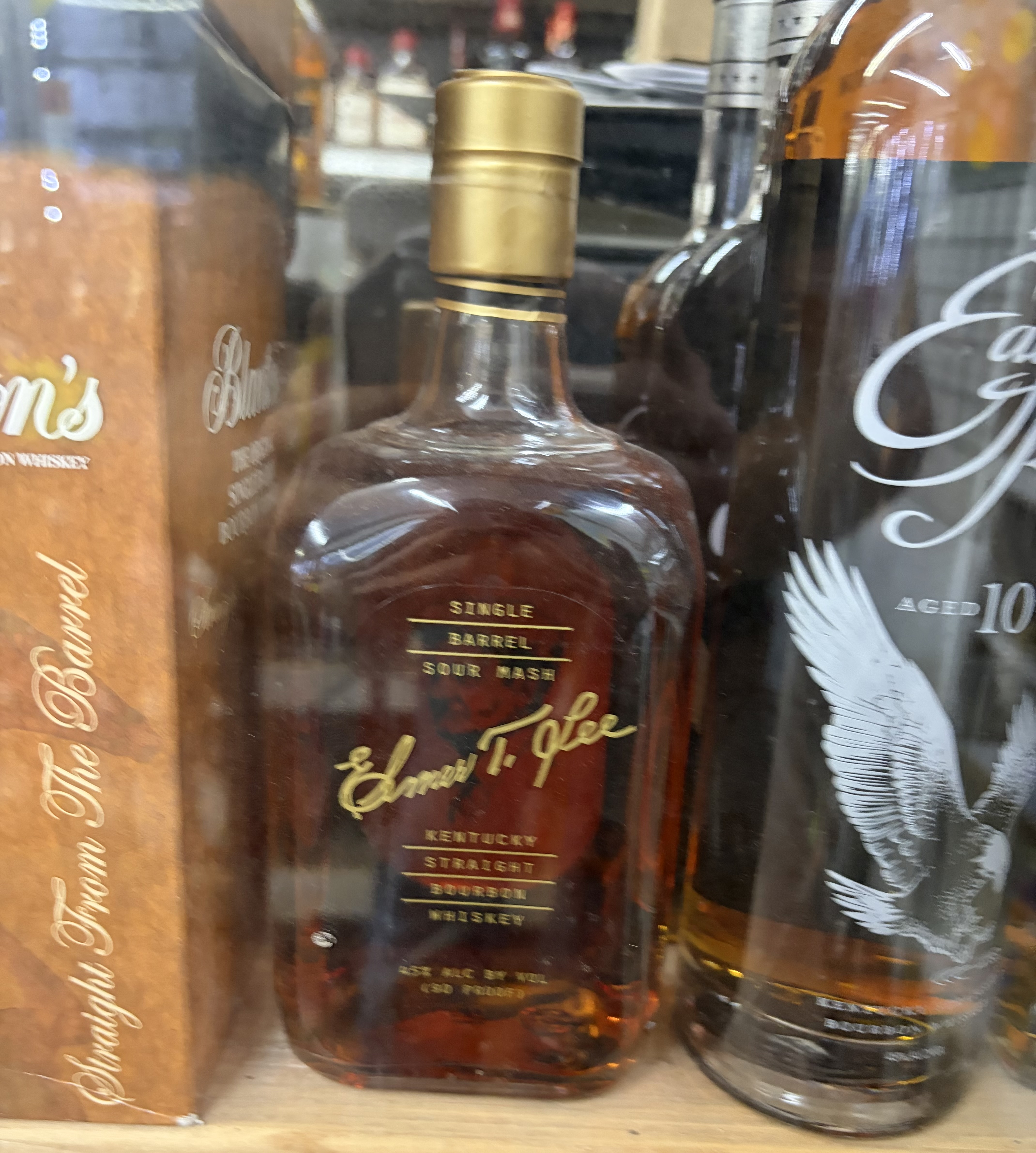 Elmer T. Lee Single Barrel Sour Mash bourbon bottle beside Eagle Rare 10-Year and Blanton's.