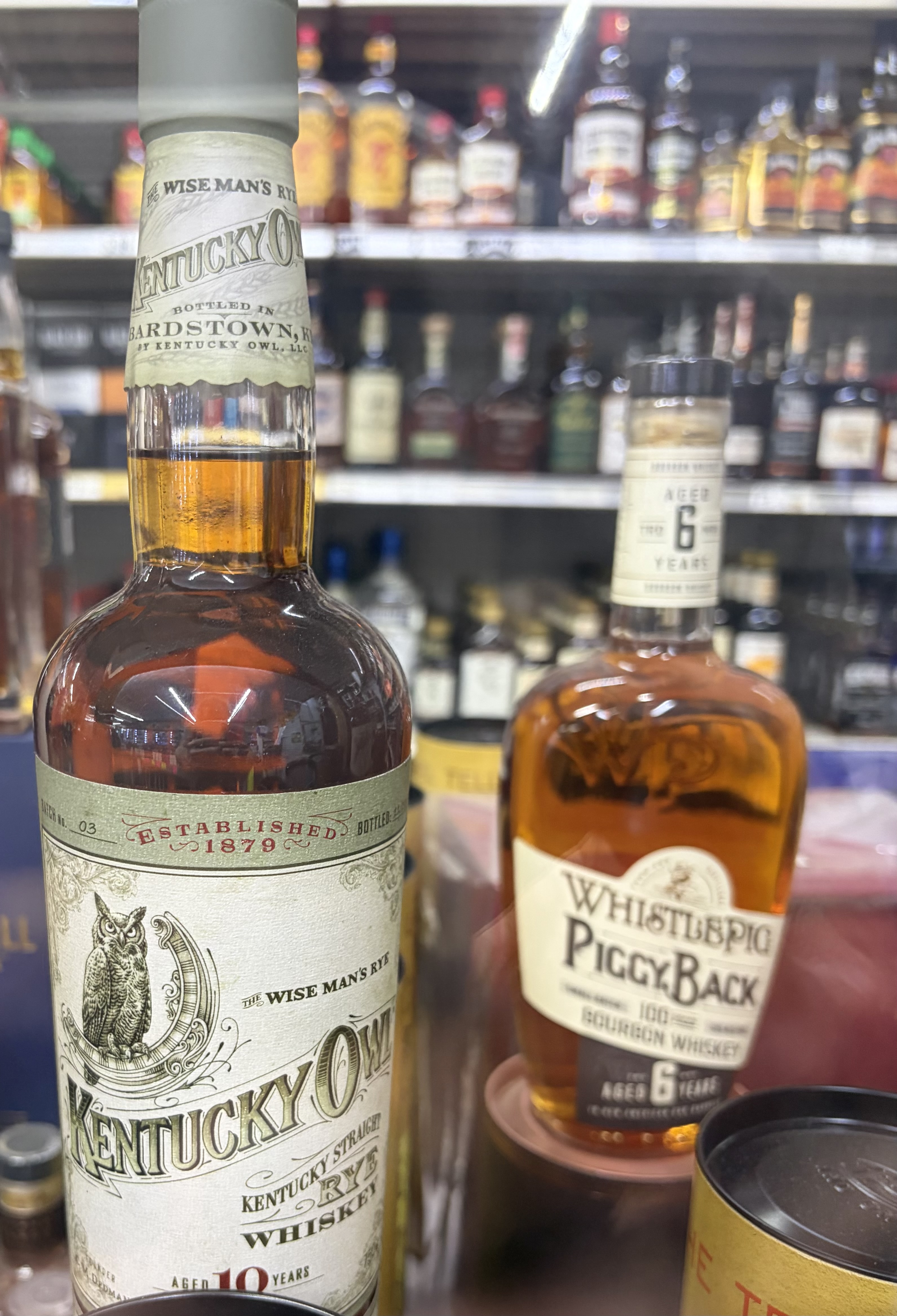 Kentucky Owl The Wise Man's Rye Aged 10 Years beside WhistlePig PiggyBack 6-Year bourbon.